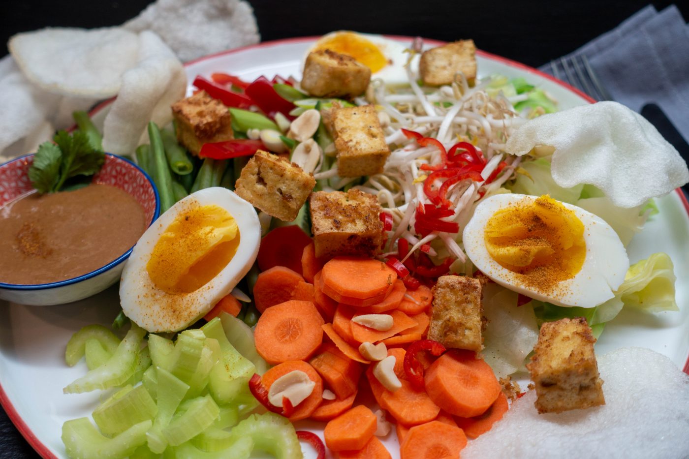 Indonesisches Gado Gado, ein bunter Gemüseteller mit gekochten Eierhälften, gebratenem Tofu, Krupuk und Erdnuss-Sauce
